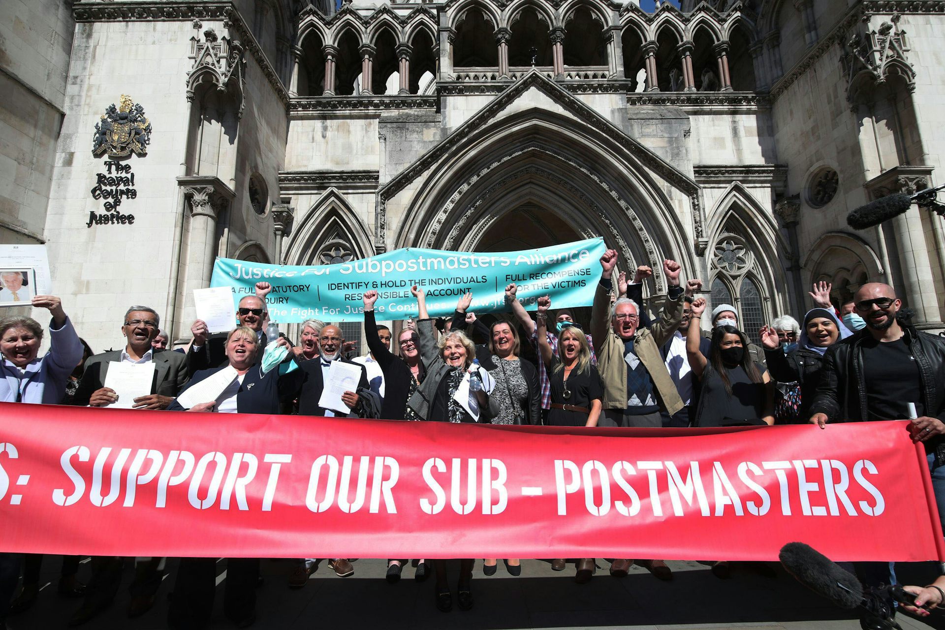 A crowd with banners celebrates outside a court.