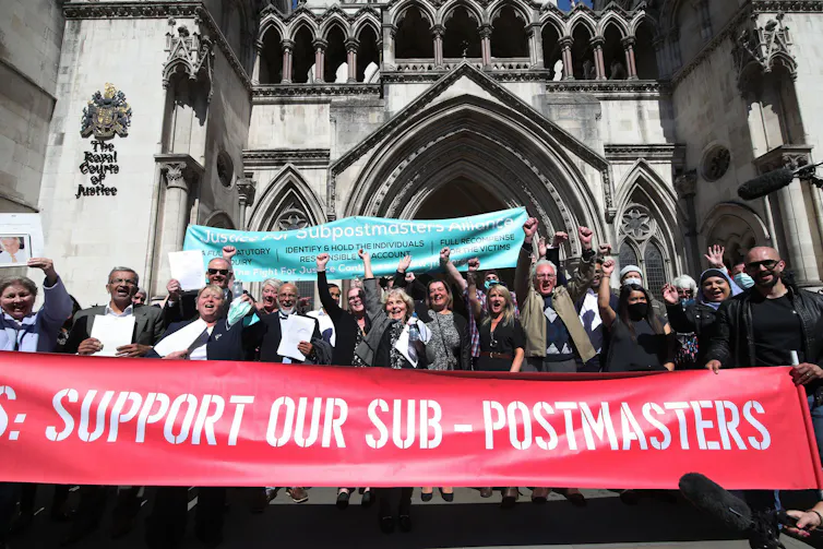 A crowd with banners celebrates outside a court.