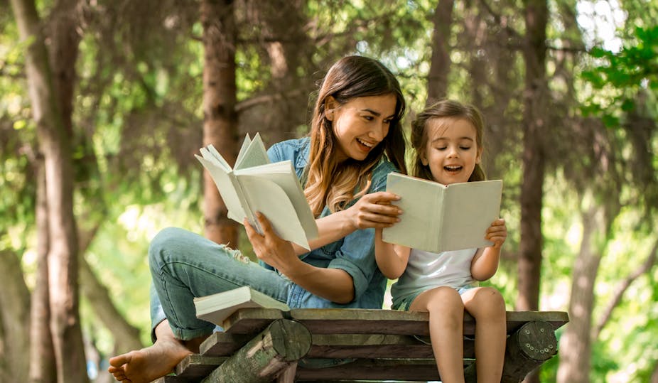 Jeune mère et fille lisant un livre dans les bois