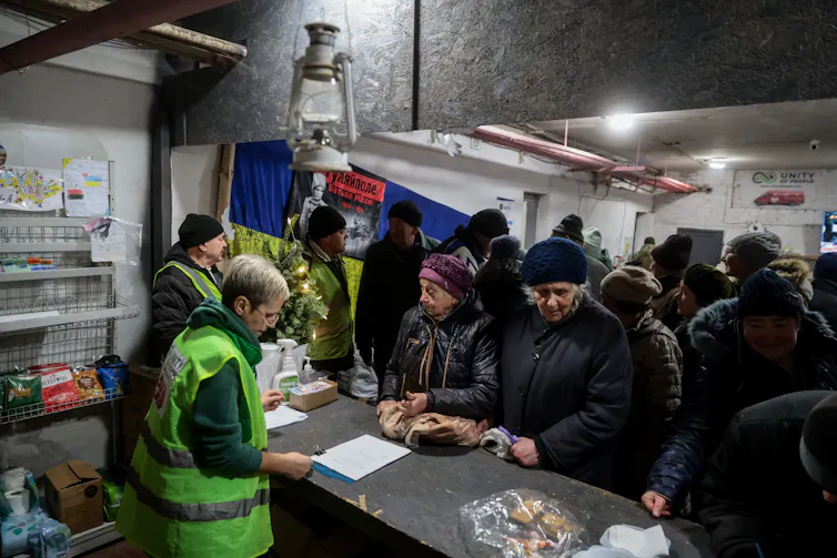 Ukrainian refugees queue for food handouts.