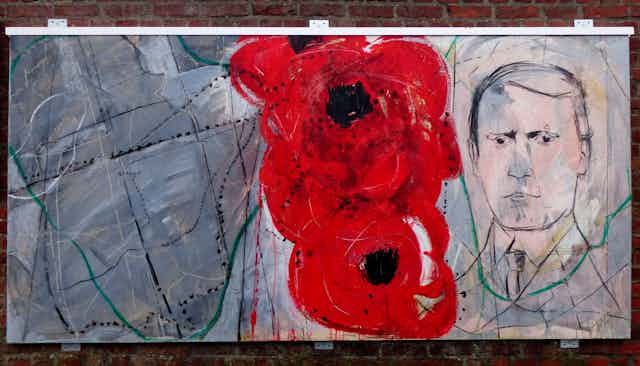 A mural depicting the face of a man next to two large illustrations of poppies. 