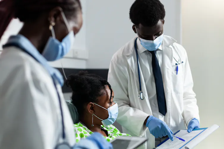 Des médecins discutent avec une petite fille d’origine africaine.