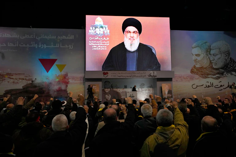 Hezbollah supporters cheer leader Hassan Nasralleh as he delivers a speech on a video screen.