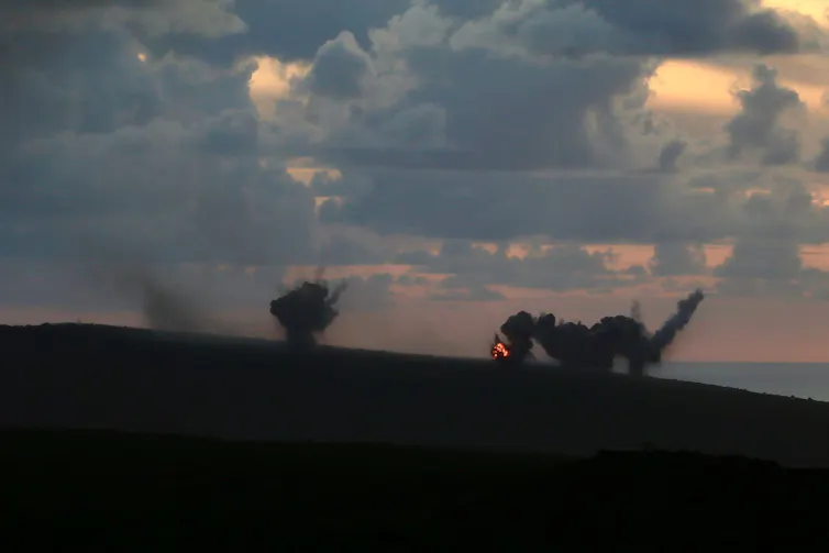 Rising smoke and an explosion on the horizon .
