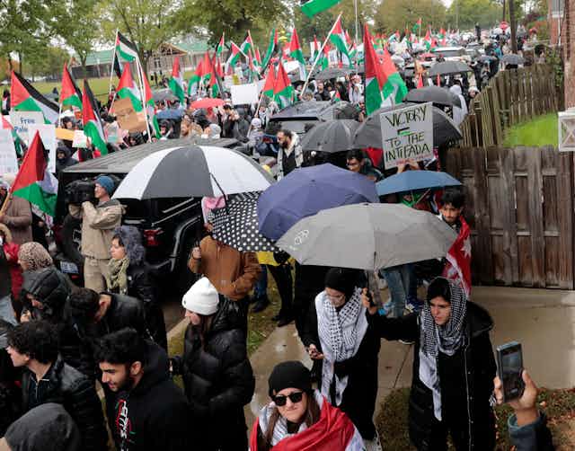 Hundreds of people are demonstrating in the rain and carrying Palestinian flags