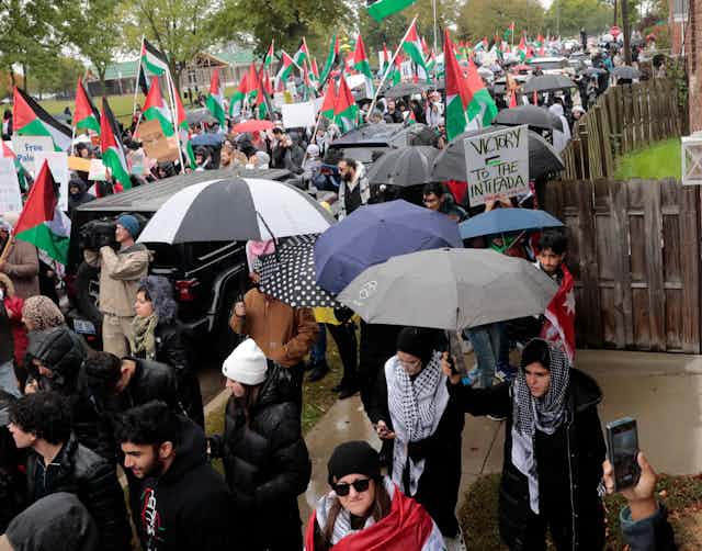 Hundreds of people are demonstrating in the rain and carrying Palestinian flags