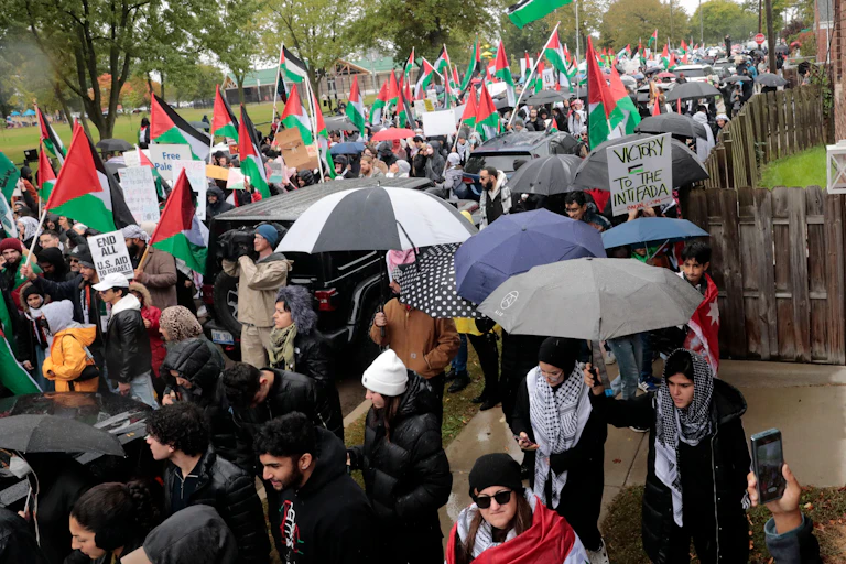 Hundreds of people are demonstrating in the rain and carrying Palestinian flags