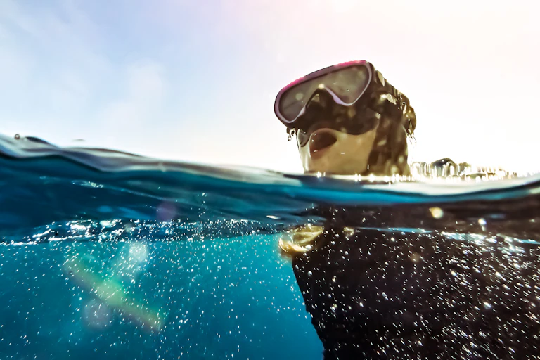 A kid with a snorkel mask comes up for a breath.