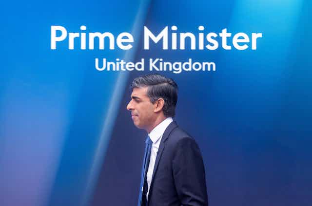 Rishi Sunak walking under a sign that reads Prime Minister, United Kingdom