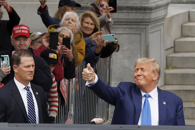 Donald Trump giving a thumbs up to crowds.