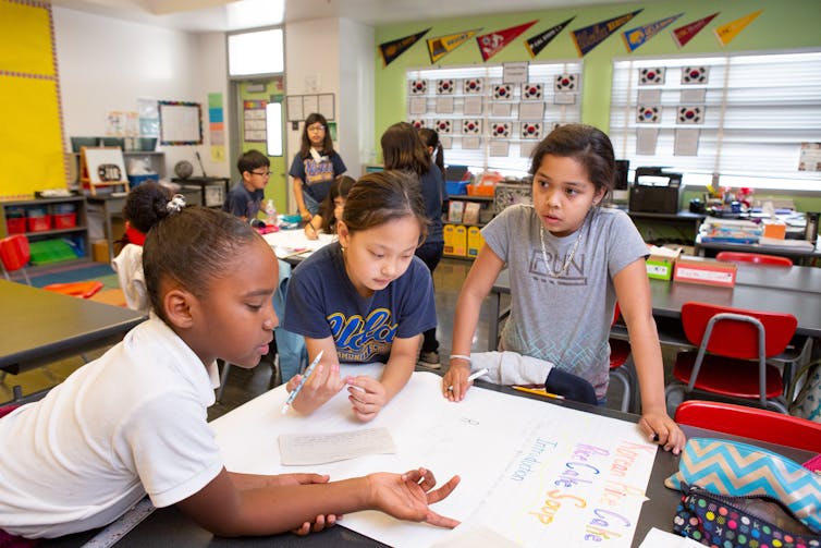 Students seen working together at desks in a classroom.