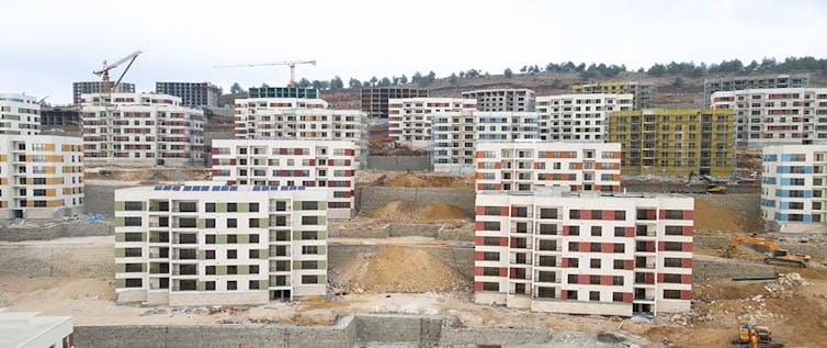 A series of apartment buildings under construction with cranes above.