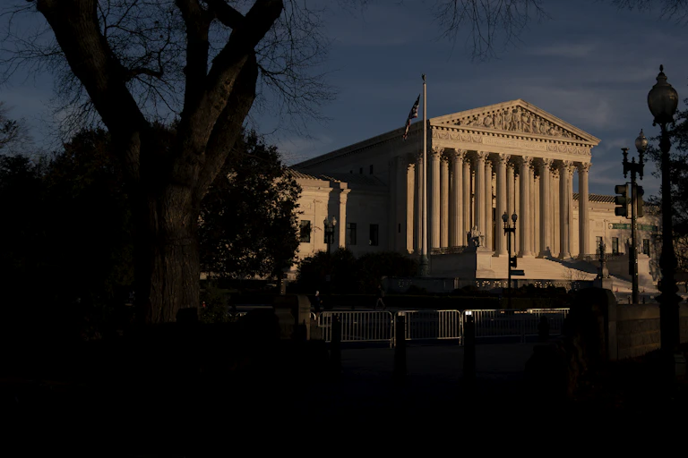 A large white, columned building against a dark blue sky.