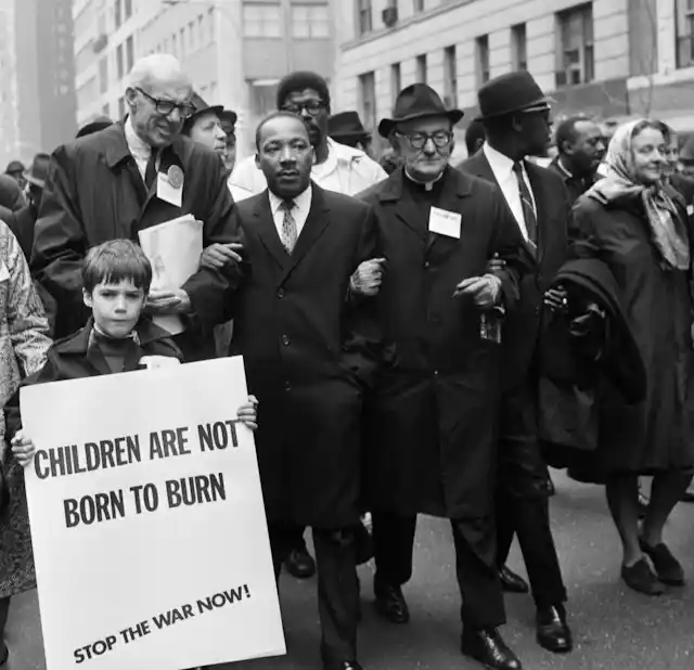 A Black man uses his arms to link with other people leading a march.
