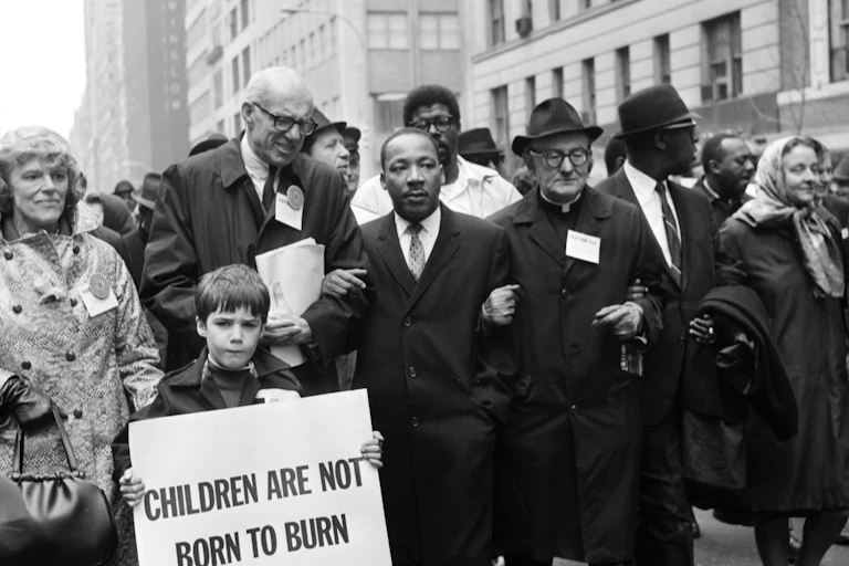 A Black man uses his arms to link with other people leading a march.
