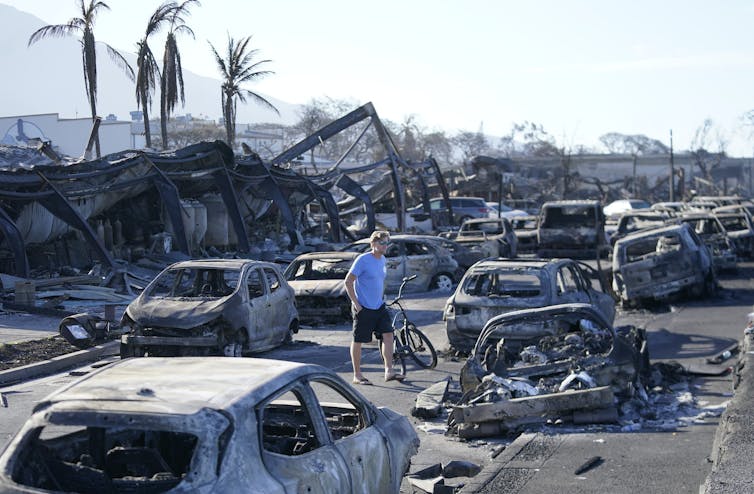 A man with a bicycle walks through a scene of destruction after the fire in Lahaina.