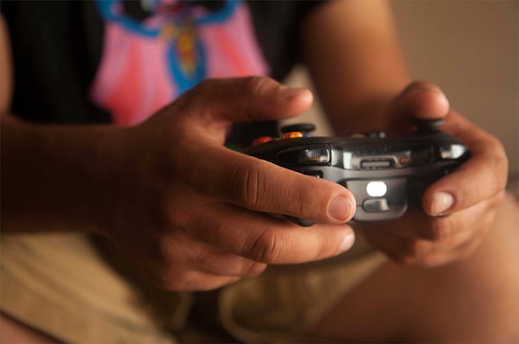 A young person holds a gaming controller.