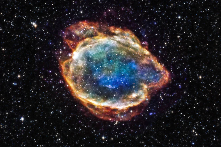 A colourful explosion of orange, blue and green against a field of stars.