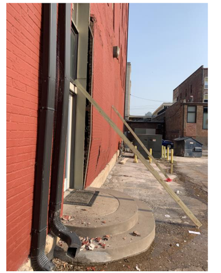 In a photo taken before the collapse, supports lean against a clearly bowed brick exterior wall of the building.