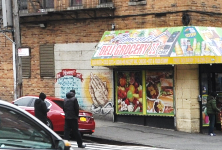 A photo of the corner of a building with a deli and a giant crack down the front support column.