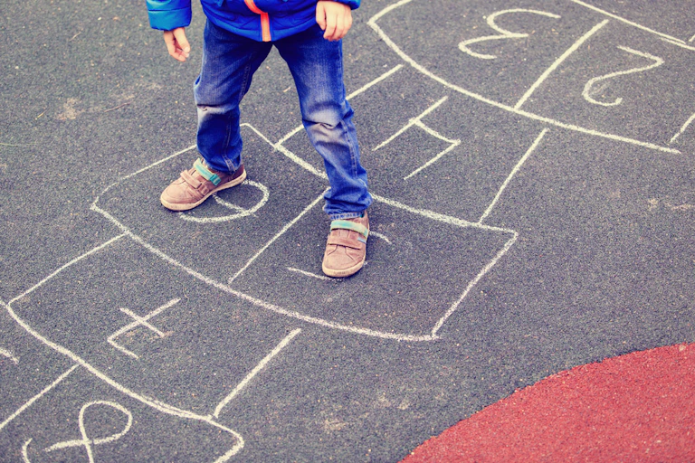 Enfant jouant à la marelle dans la cour d'une école