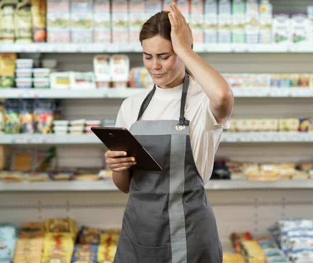 Woman working in supermarket stressed