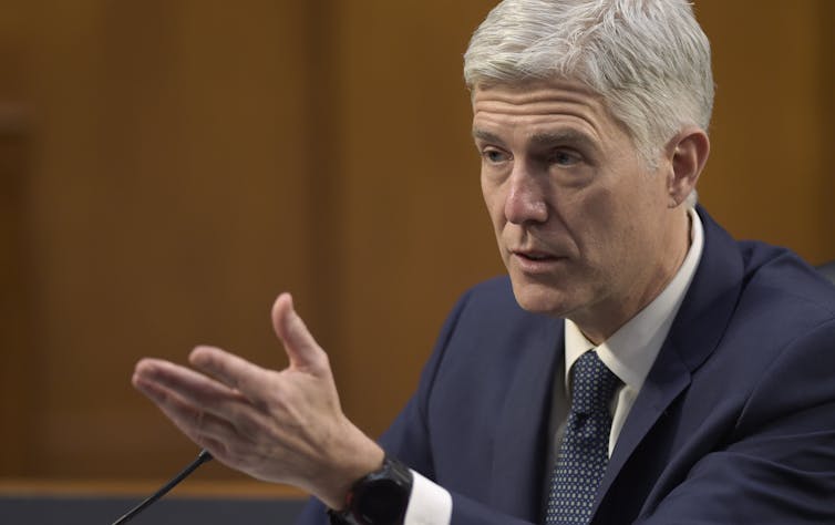 Gorsuch, seated, gestures during testimony.