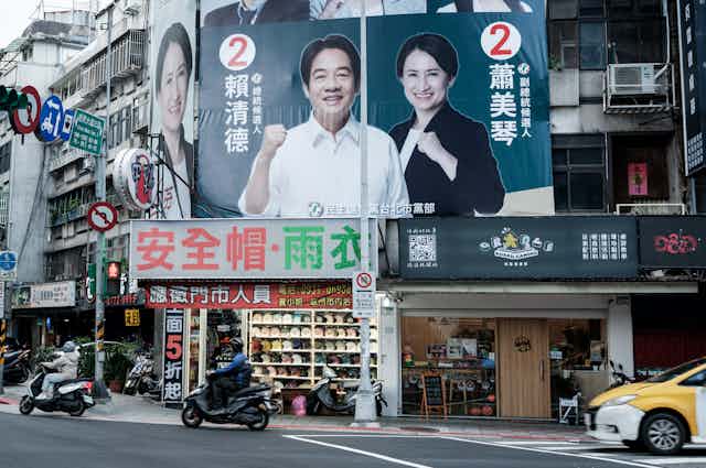 A billboard shows a smiling man and women raising their fists.