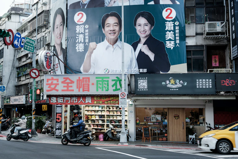 A billboard shows a smiling man and women raising their fists.