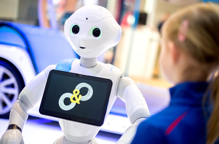 A child stands in front of Pepper the robot