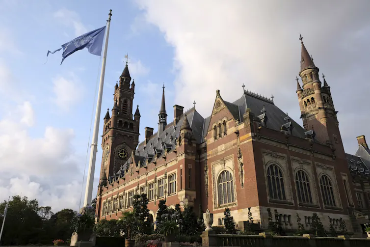 An exterior of a grand, old, brick palace with a United Nations flag flying out the front.