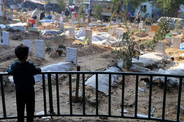 A child looks out over dozens of makeshift graves
