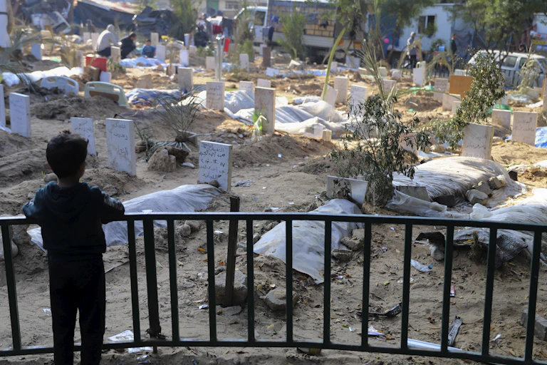 A child looks out over dozens of makeshift graves