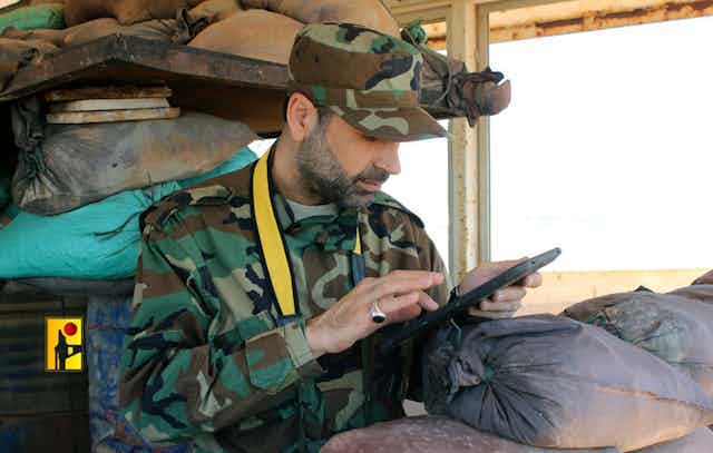A man in military fatigues taps into a tablet.