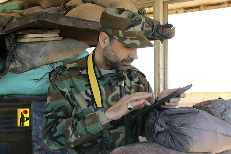 A man in military fatigues taps into a tablet.