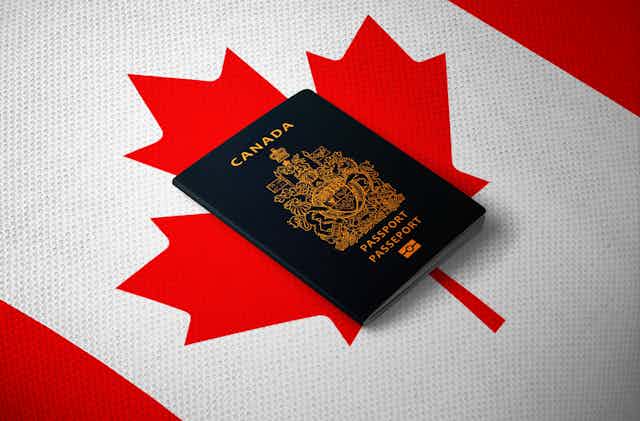A Canadian passport sits on a Canadian flag.