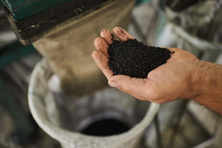 A hand cupping a black powder.