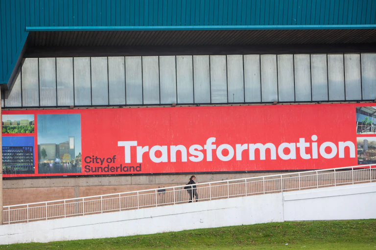 Person walking up stairs in front of a large advert for the city of Sunderland.