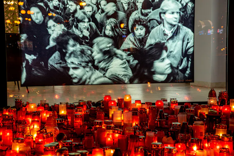 Candles in front of an old black-and-white photograph of people huddling together.