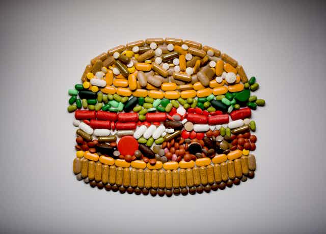 Assortment of colorful pills arranged in the shape of a hamburger