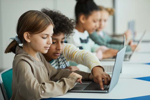 a row of children on laptops