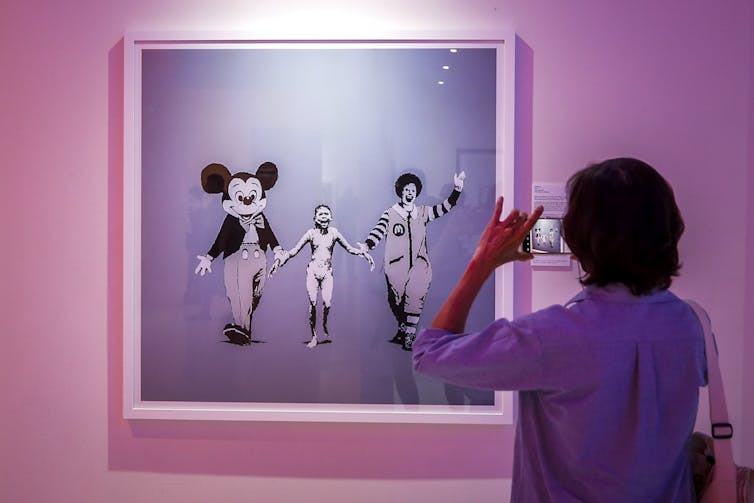 A framed image of Mickey Mouse, the Napalm girl, and Ronald McDonald.