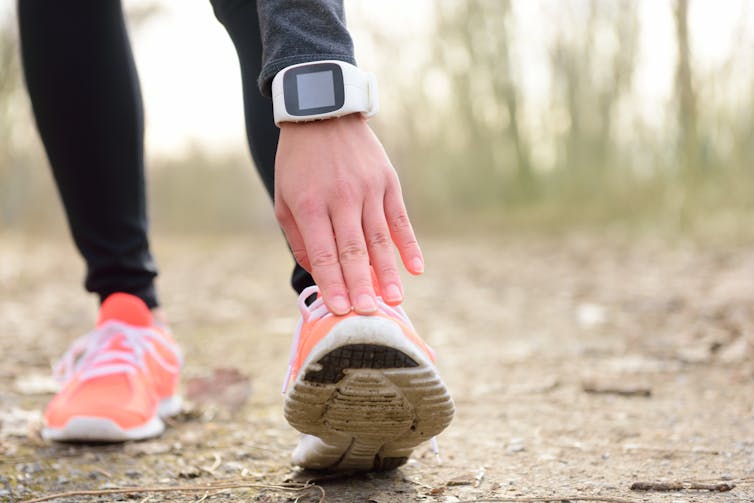 A hand with a smartwatch around the wrist stretching.