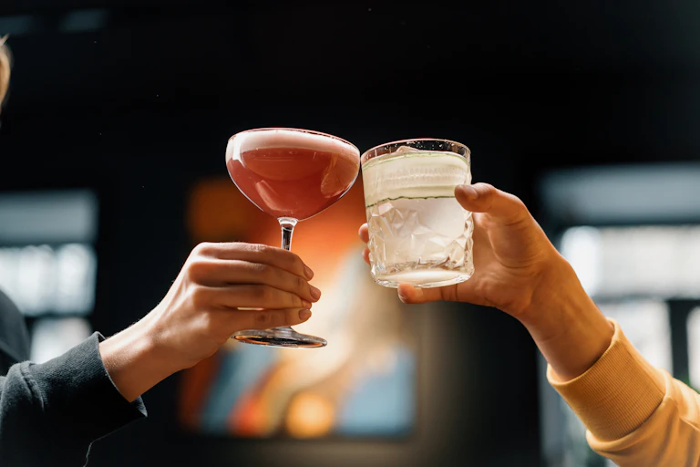 Dos manos que sostienen dos bebidas alcohólicas