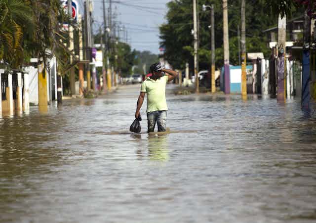 Un homme marche dans une rue inondée après le passage de l'ouragan Maria en 2017en République dominicaine dominEn 2017, l'ouragan Maria a causé des dommages en République dominicaine estimés à 226 % du produit intérieur brut du pays.