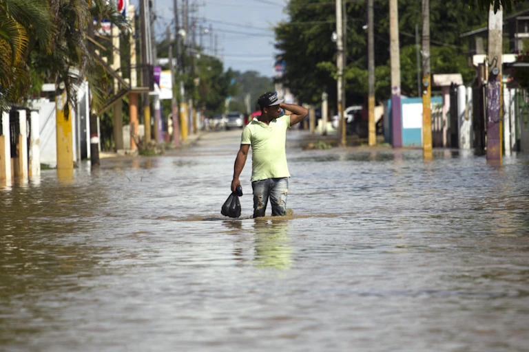 Un homme marche dans une rue inondée après le passage de l'ouragan Maria en 2017en République dominicaine dominEn 2017, l'ouragan Maria a causé des dommages en République dominicaine estimés à 226 % du produit intérieur brut du pays.