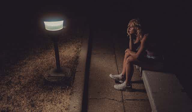 Femme anxieuse assise dans la rue la nuit