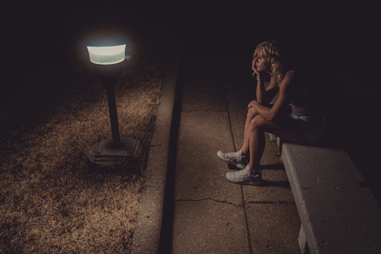 Femme anxieuse assise dans la rue la nuit