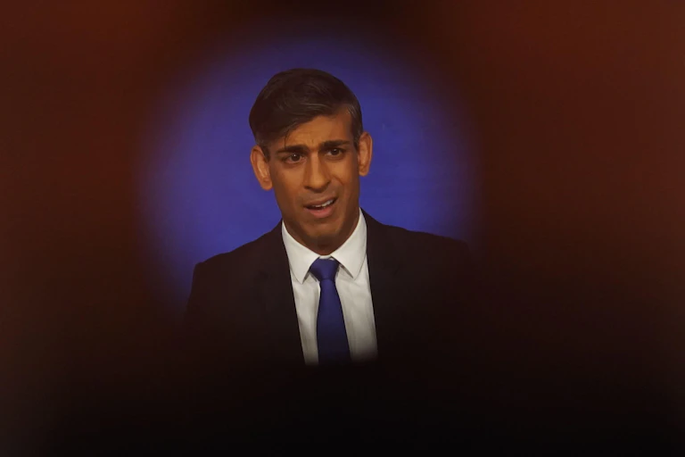Rishi Sunak seen through a camera lens, flanked by union flags.