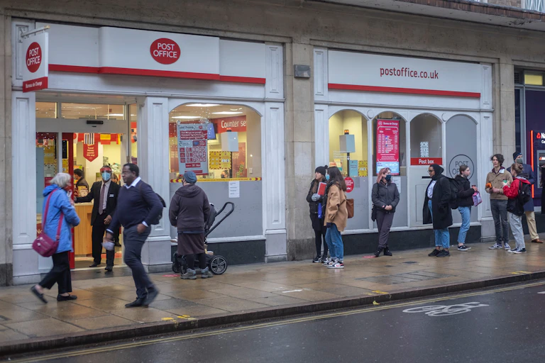 People line up outside a Post Office branch in Cambridge.